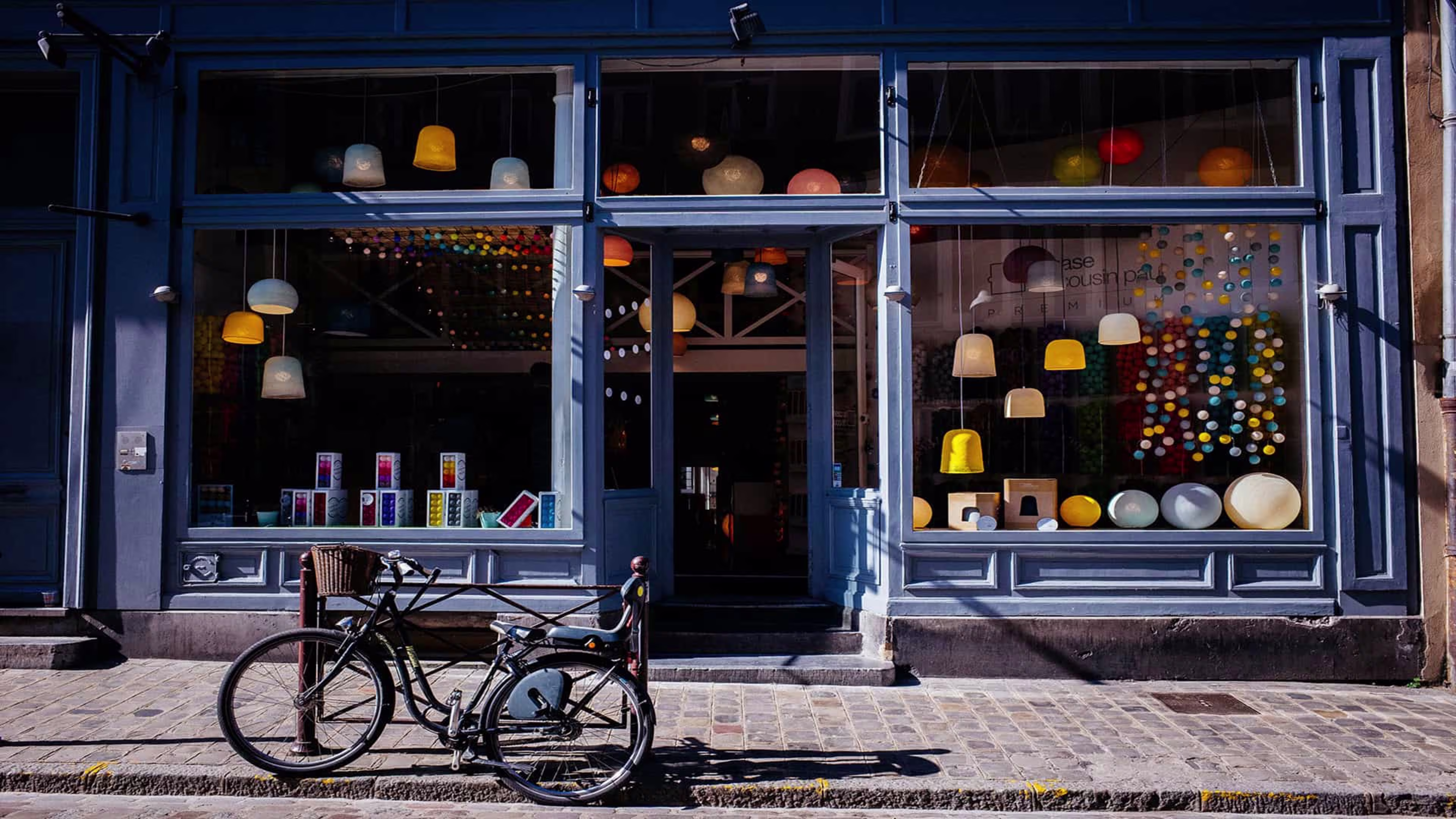 A charming local storefront with large windows and a bicycle parked on the sidewalk out front, symbolizing small business and community life.