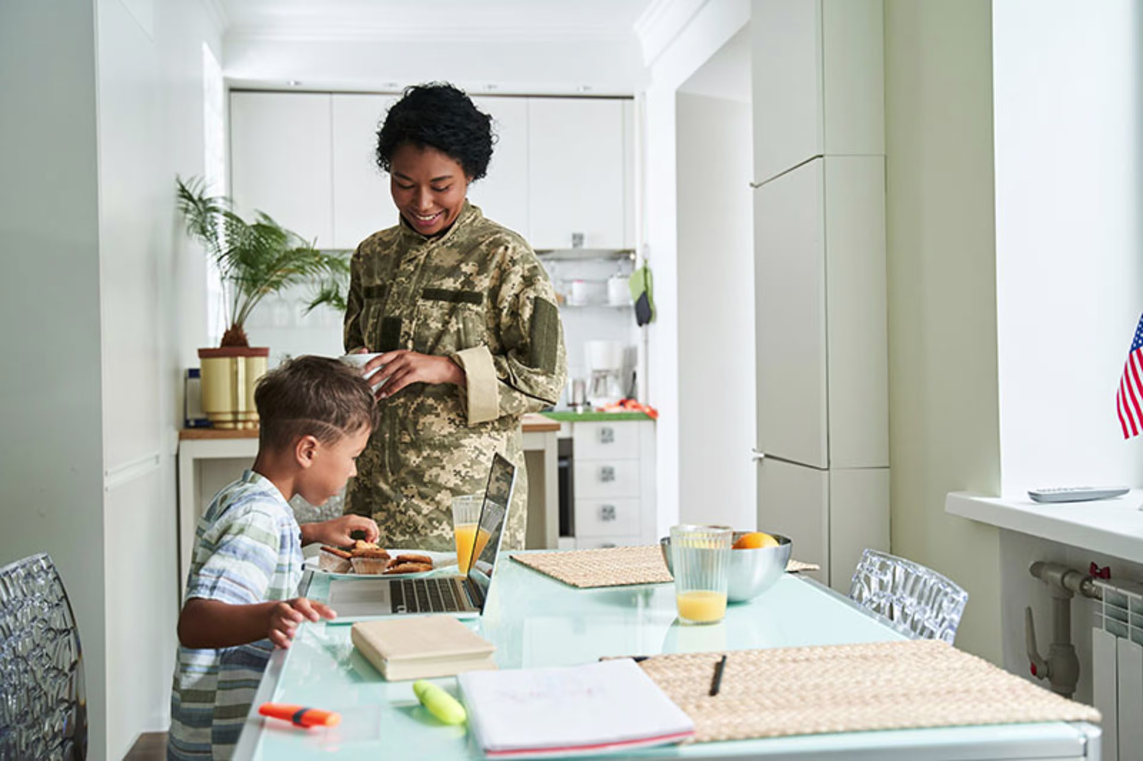 Mother in the kitchen with her son eating breakfast in a military service uniform, capturing everyday moments made possible by VA Mortgage Loans, VA Home Loans, and home improvement support through a VA Loan.