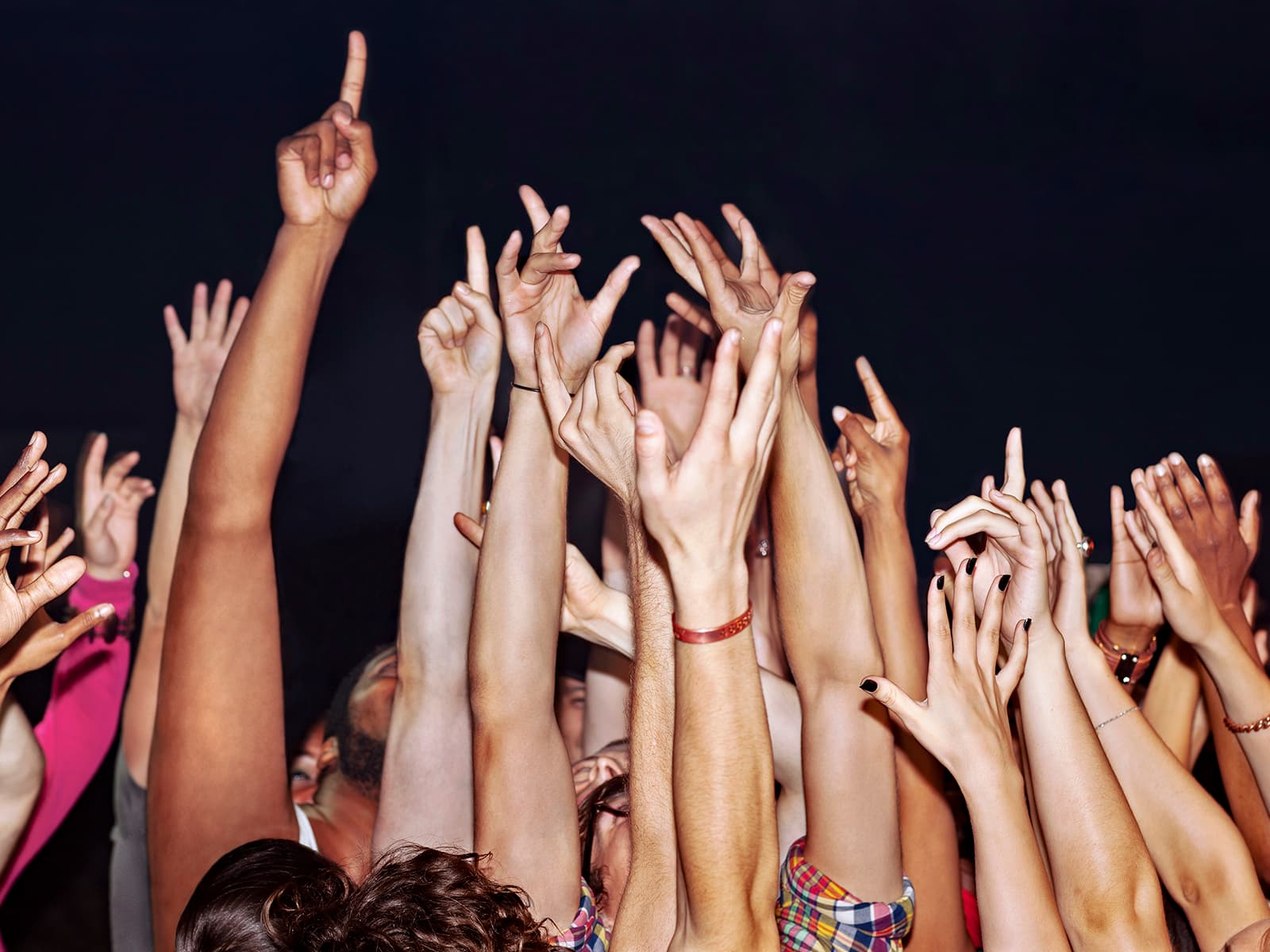 Crowd of people at a concert with their hands in the air