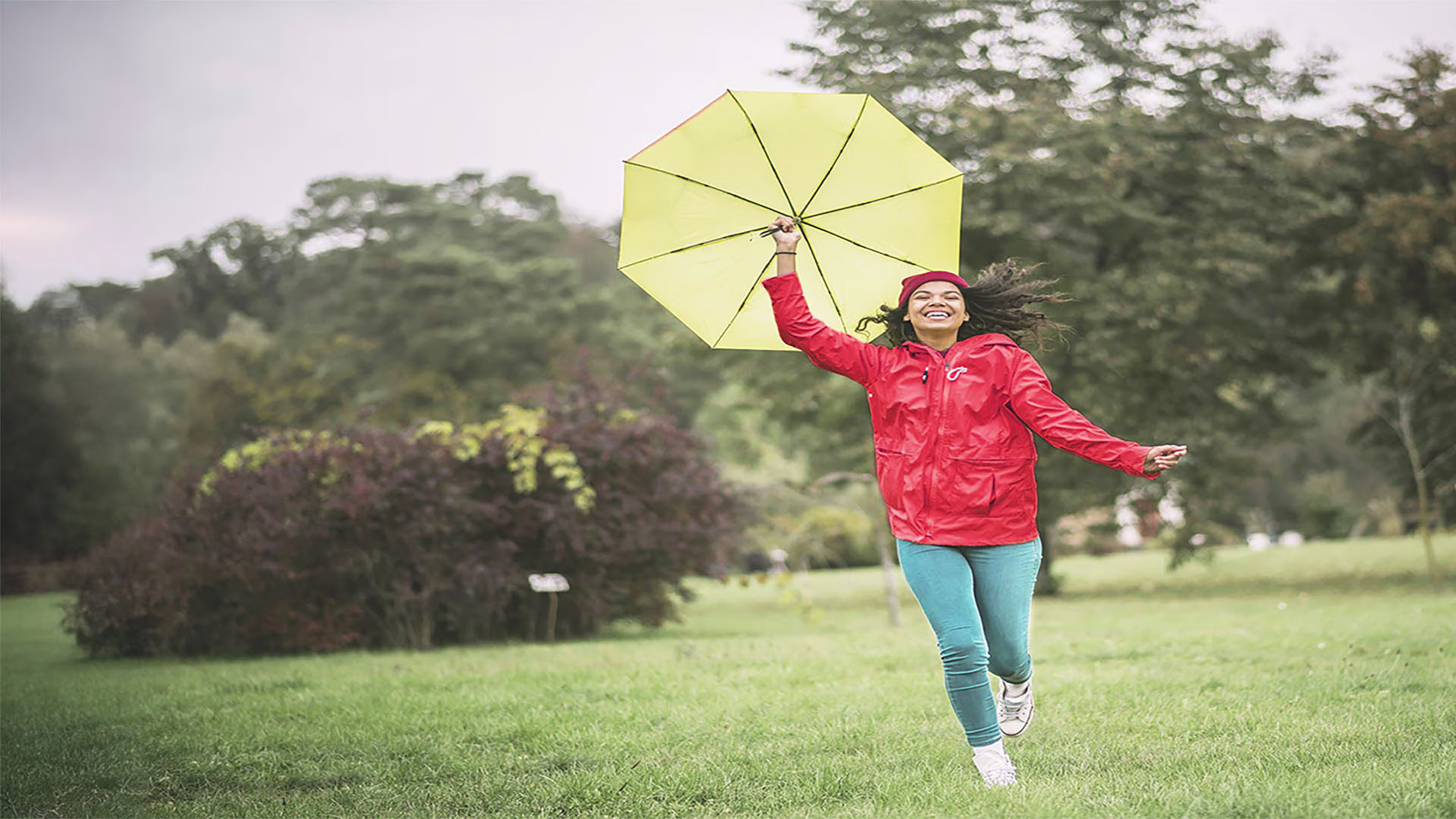 Woman running in the rain in a red jacket—Westerra supports your journey with flexible mortgage options designed for Colorado’s ever-changing conditions.