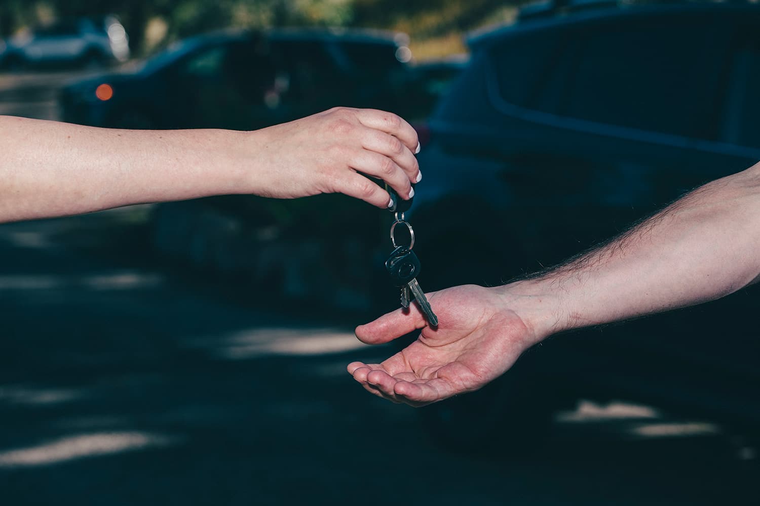 Person's hand dropping keys in another person's hand