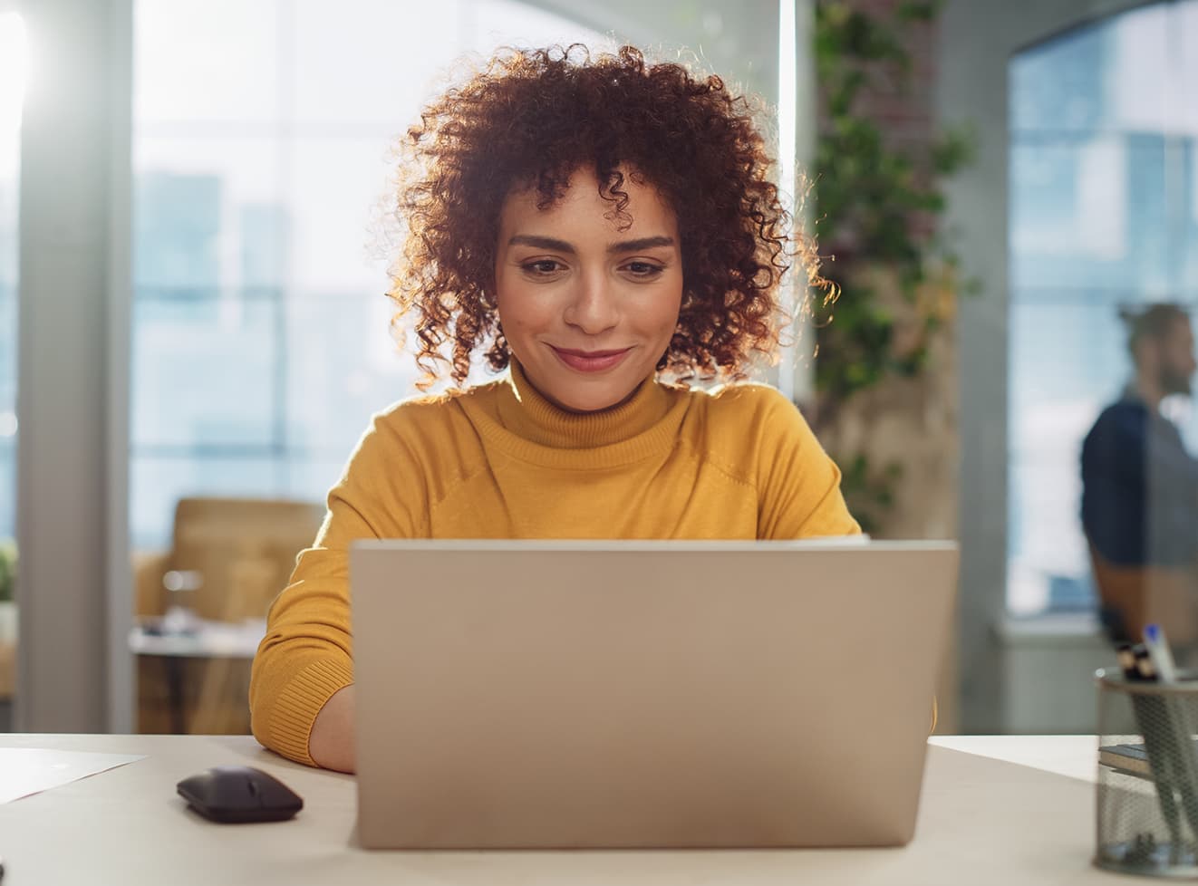 Woman in a yellow shirt working on a laptop