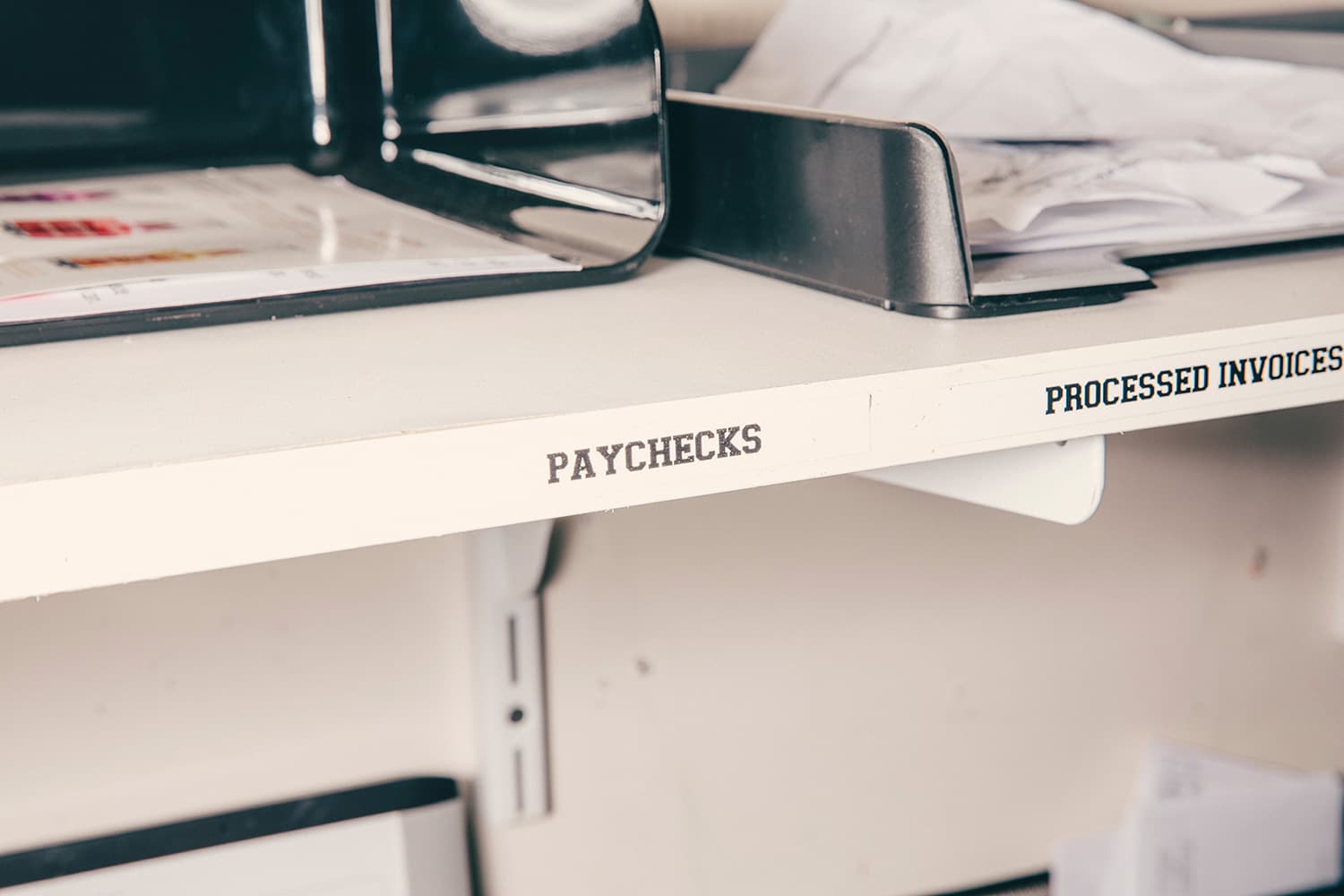 Shelf labelled "Paychecks" and "Processed Invoices"