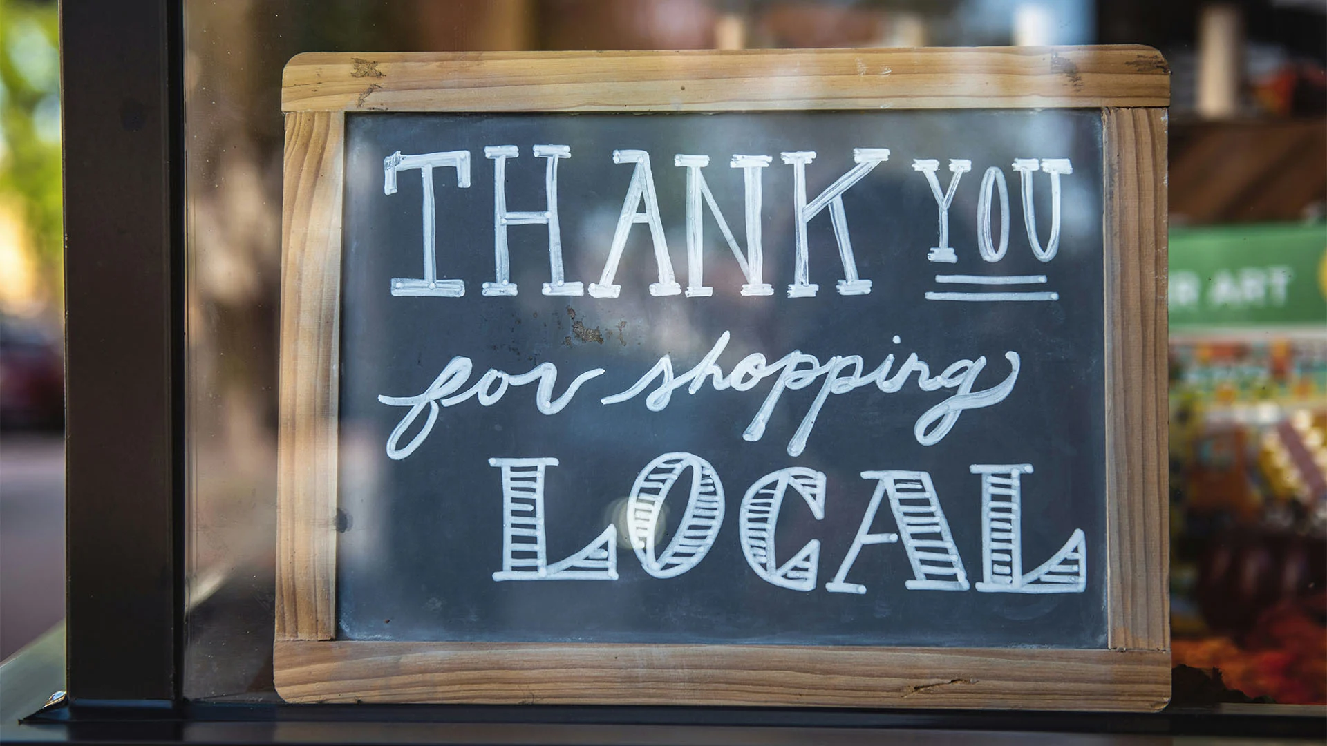 Shop sign reading 'Thank you for shopping local,' supported by Westerra Small Business Credit Card solutions.