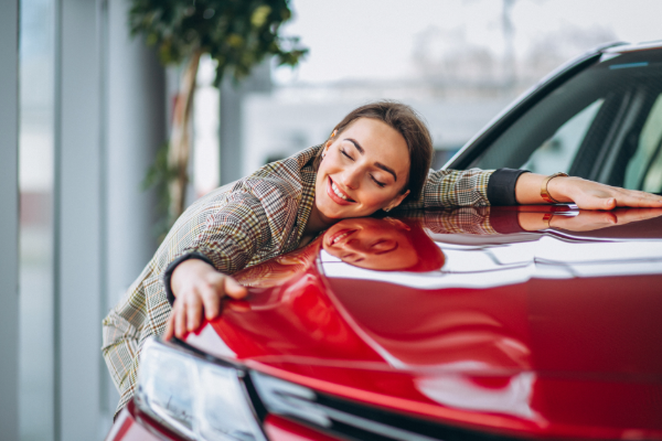 Photo of a young woman hugging the hood of a red car