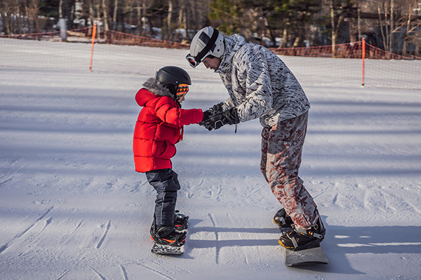 Father teaching his son to snowboard in the Colorado mountains, with overlay text 'Adjustable Rate Mortgage'—Westerra helps families grow with flexible home financing options.