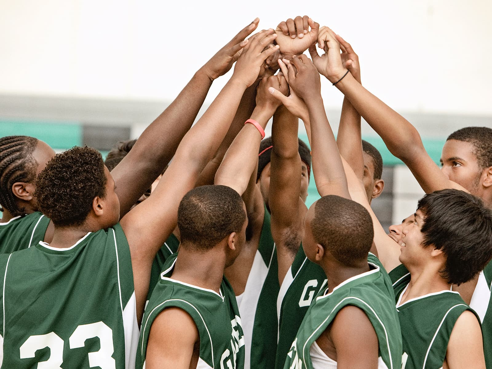 Basketball team with hands in the air in a team huddle