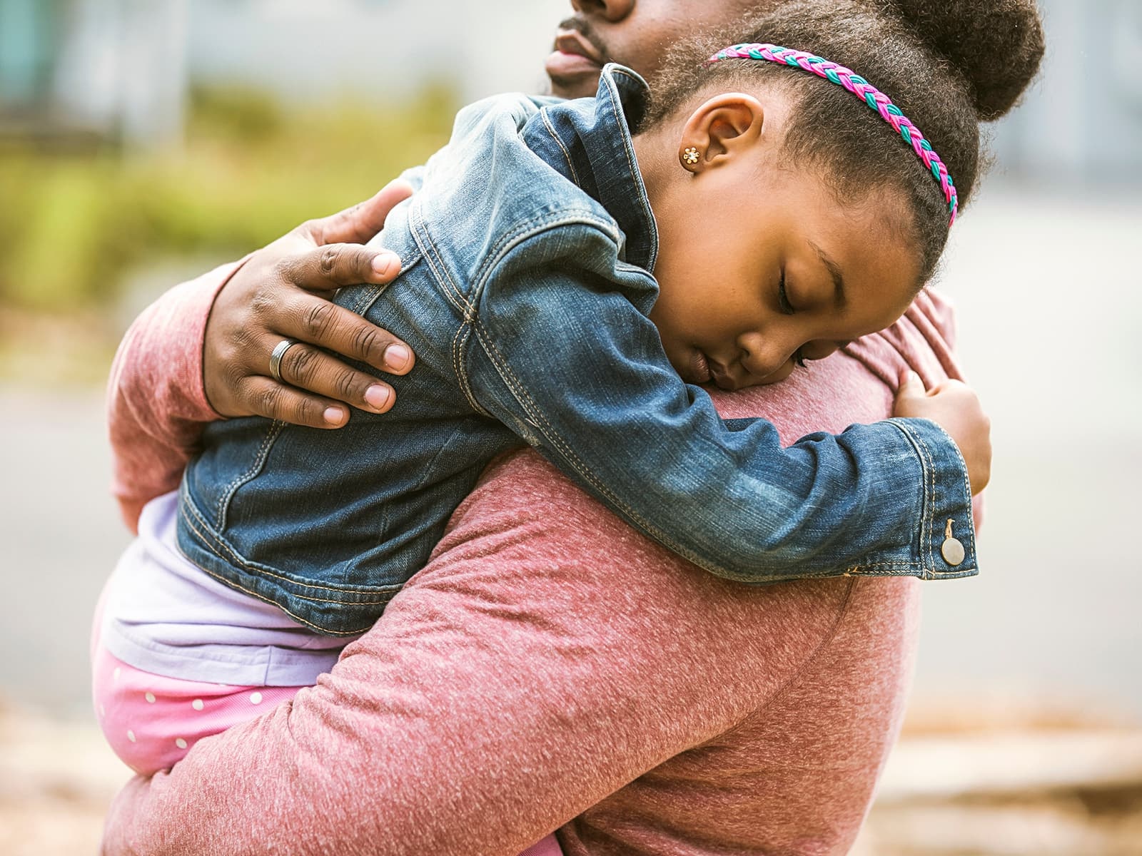 Man holding his young sleeping daughter on his shoulder