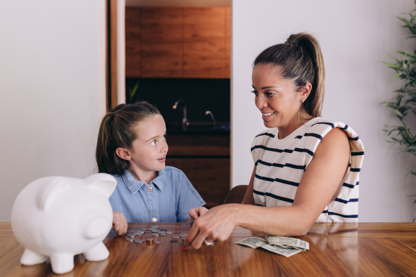 Photo of a woman and girl counting the money next to a piggy bank