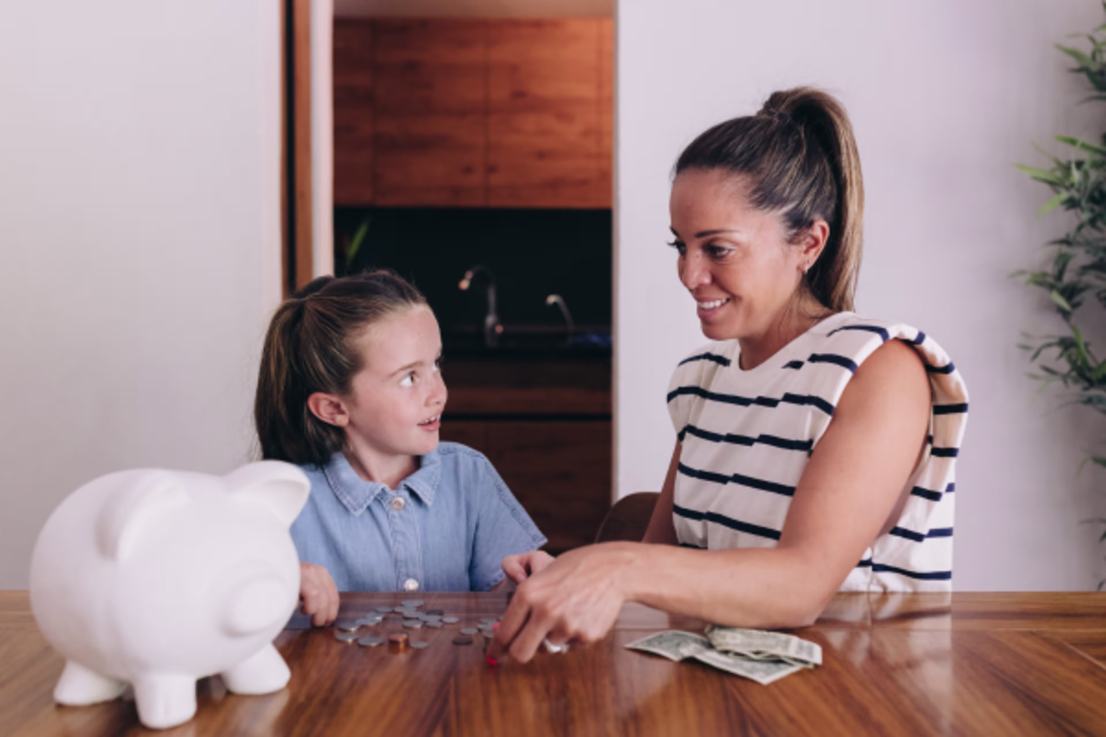 Photo of a woman and girl counting the money next to a piggy bank