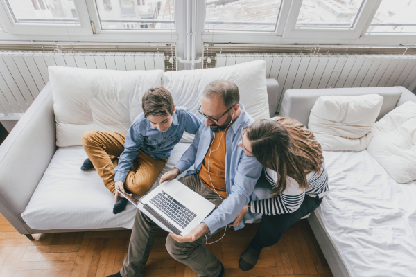 Top down photo of a family looking at a laptop together on the couch