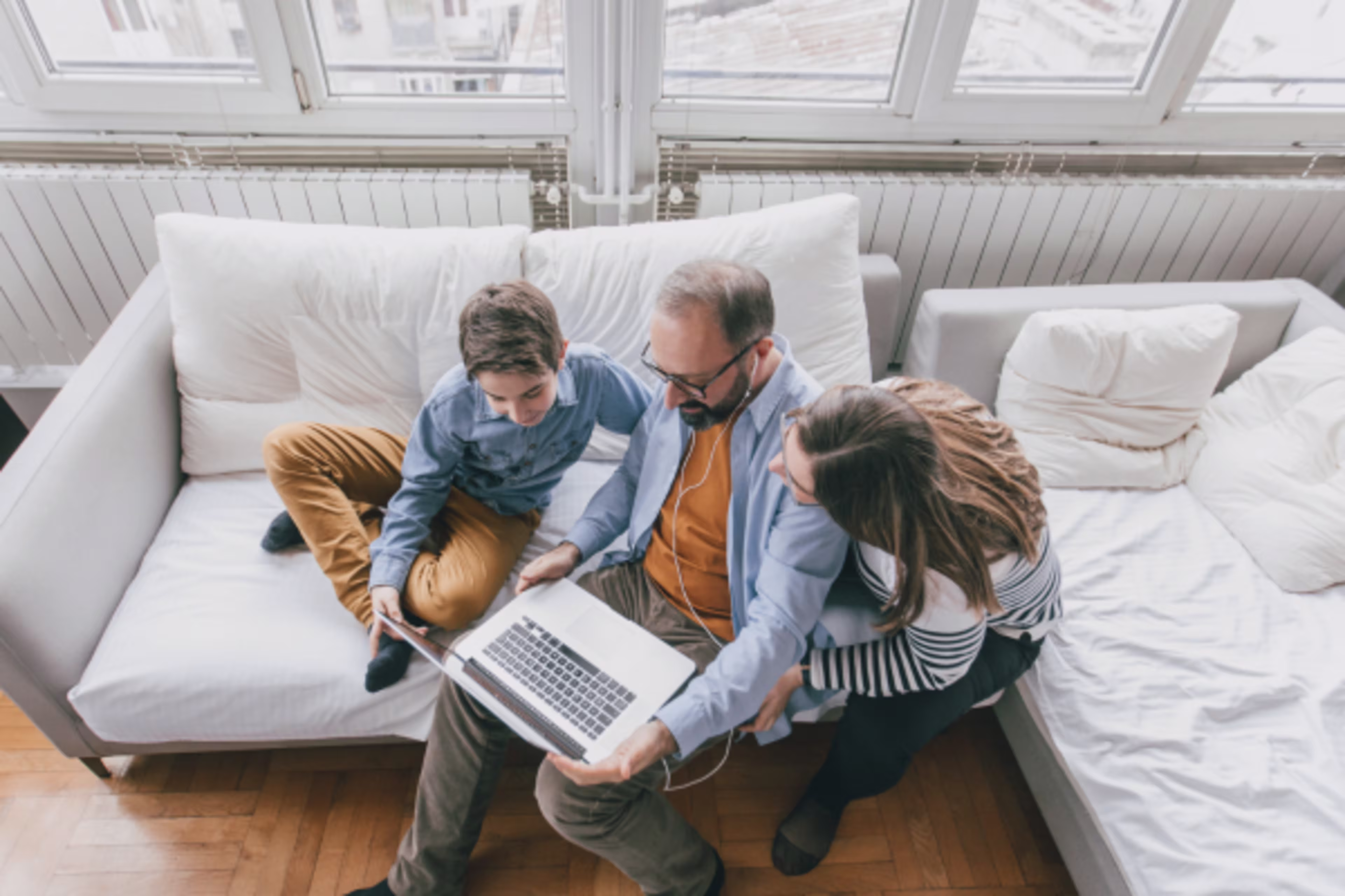 Top down photo of a family looking at a laptop together on the couch