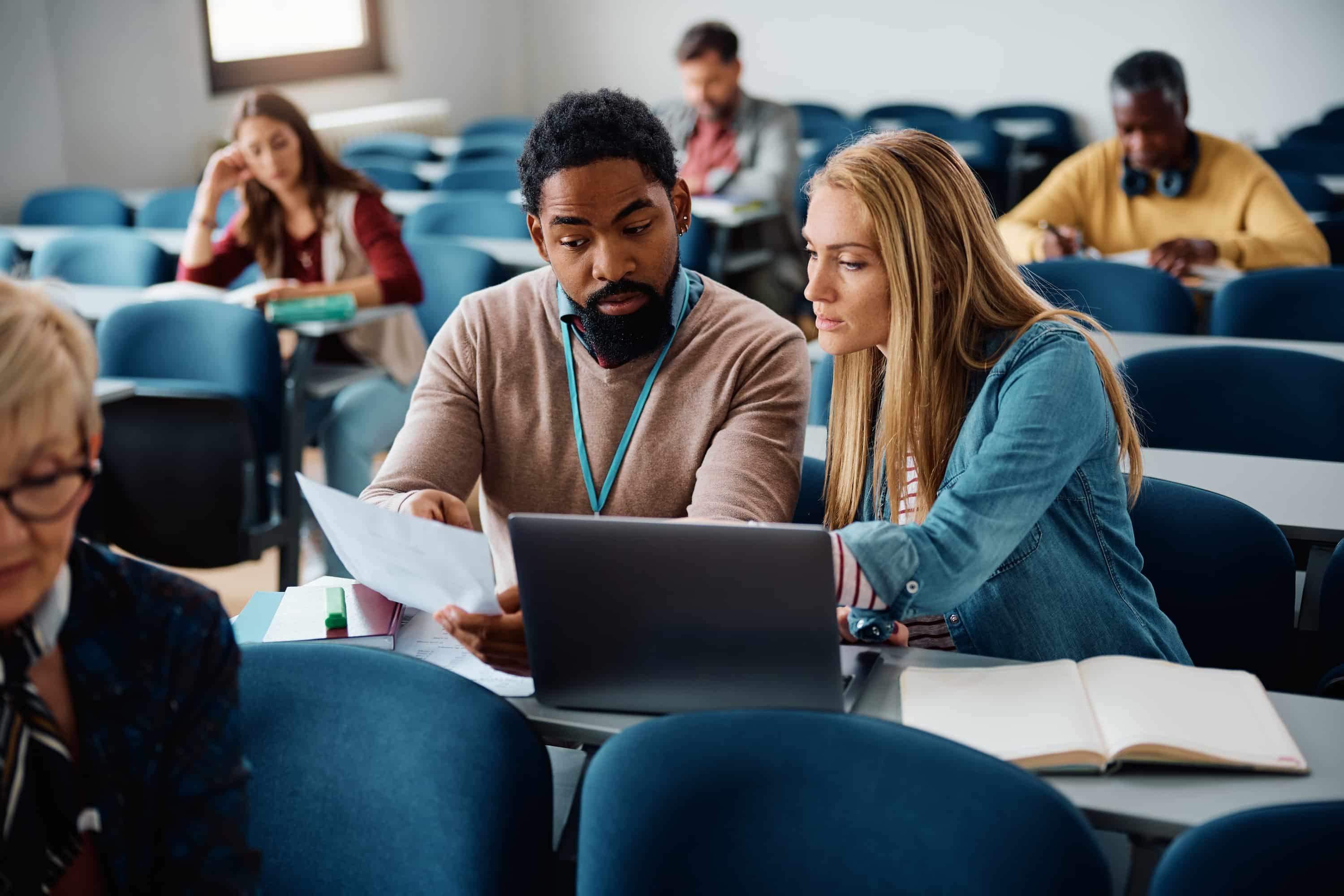 Photo of a man and a woman looking at a piece of paper together in a classroom