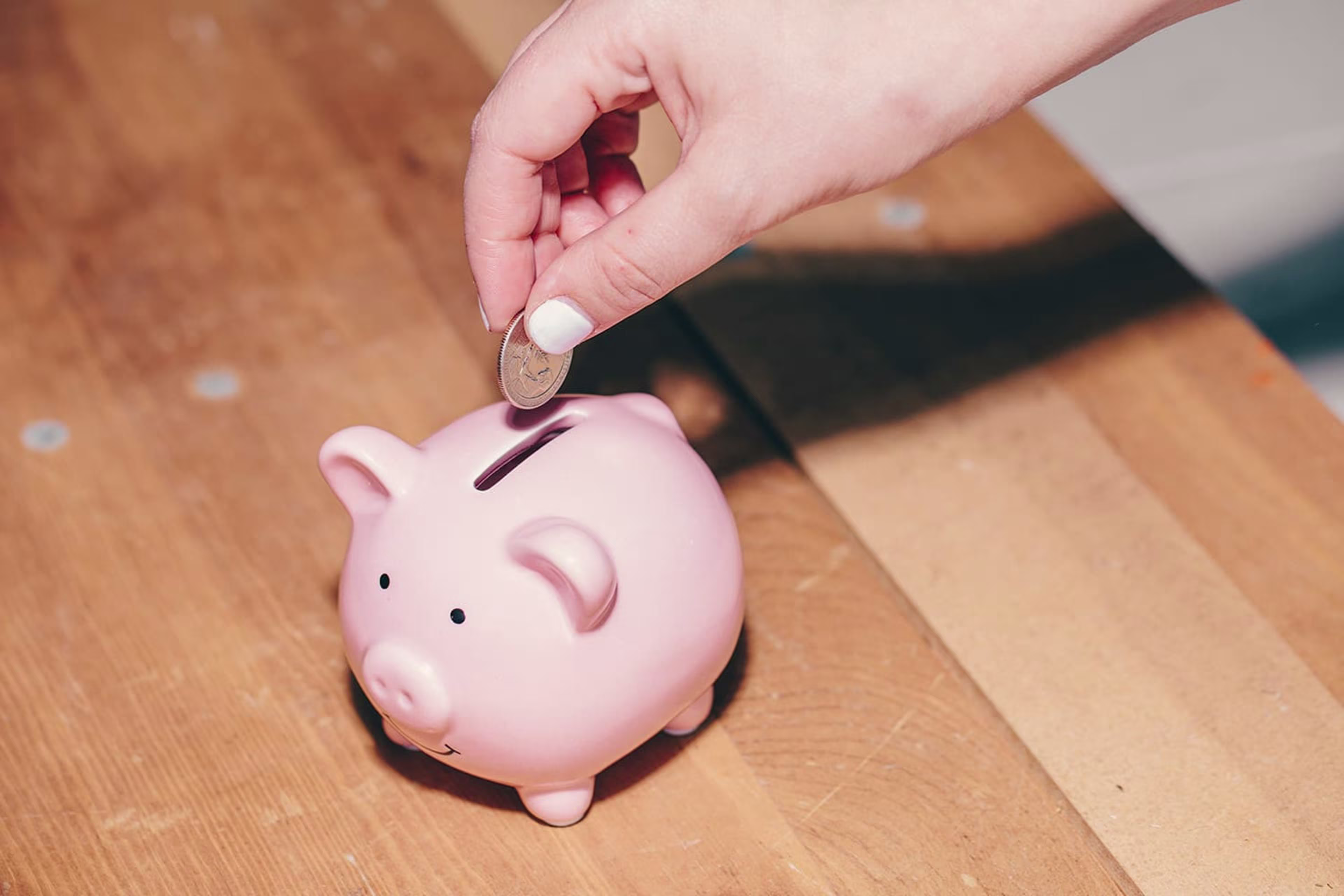 Person dropping a quarter into a piggy bank