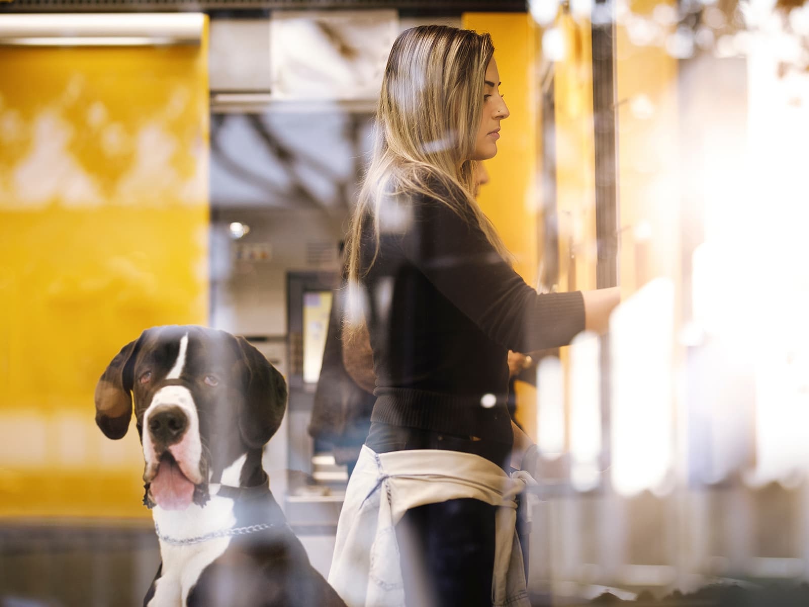 Woman using ATM with her dog behind her