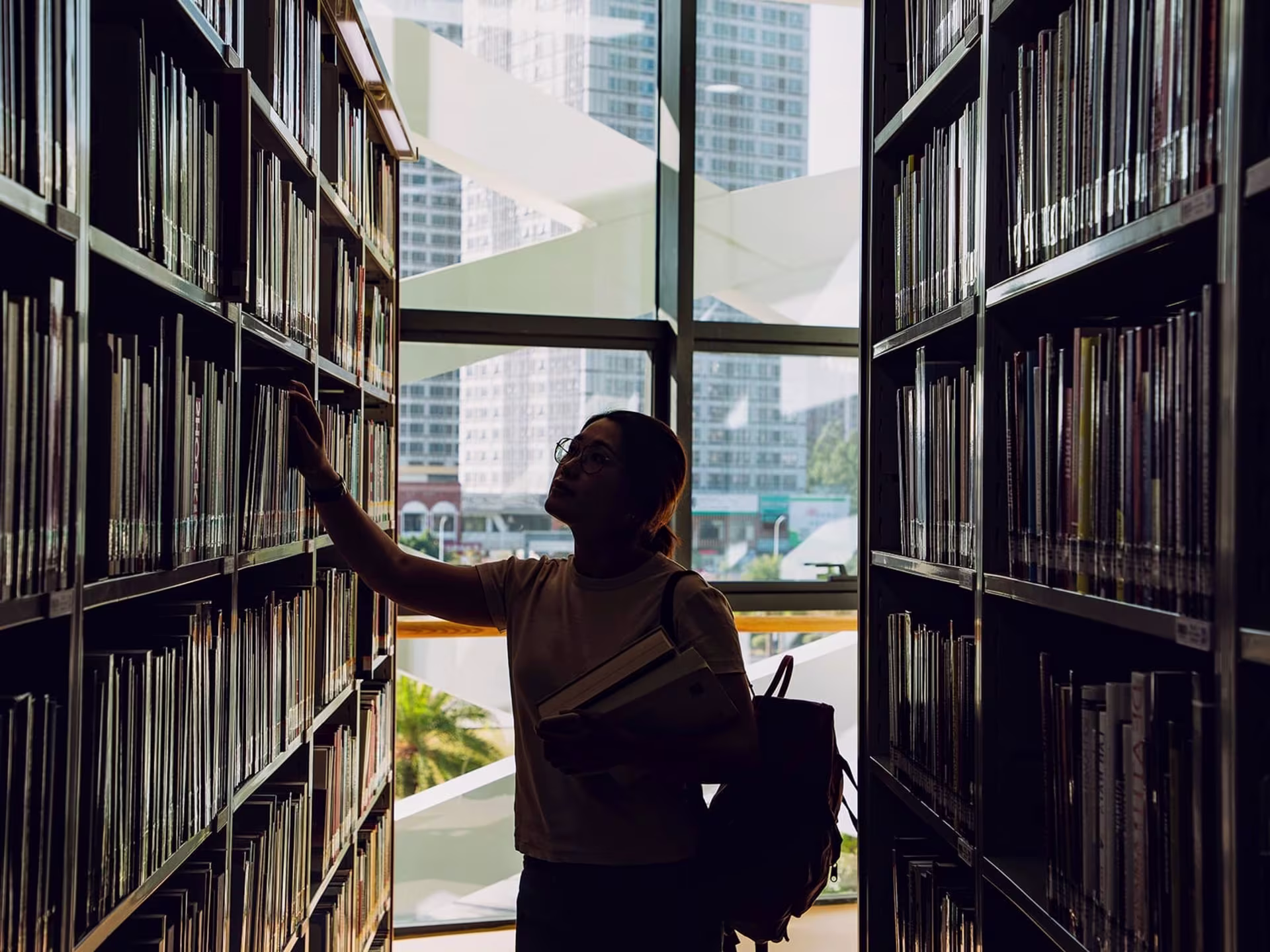 Girl in library pulling a book off the shelf