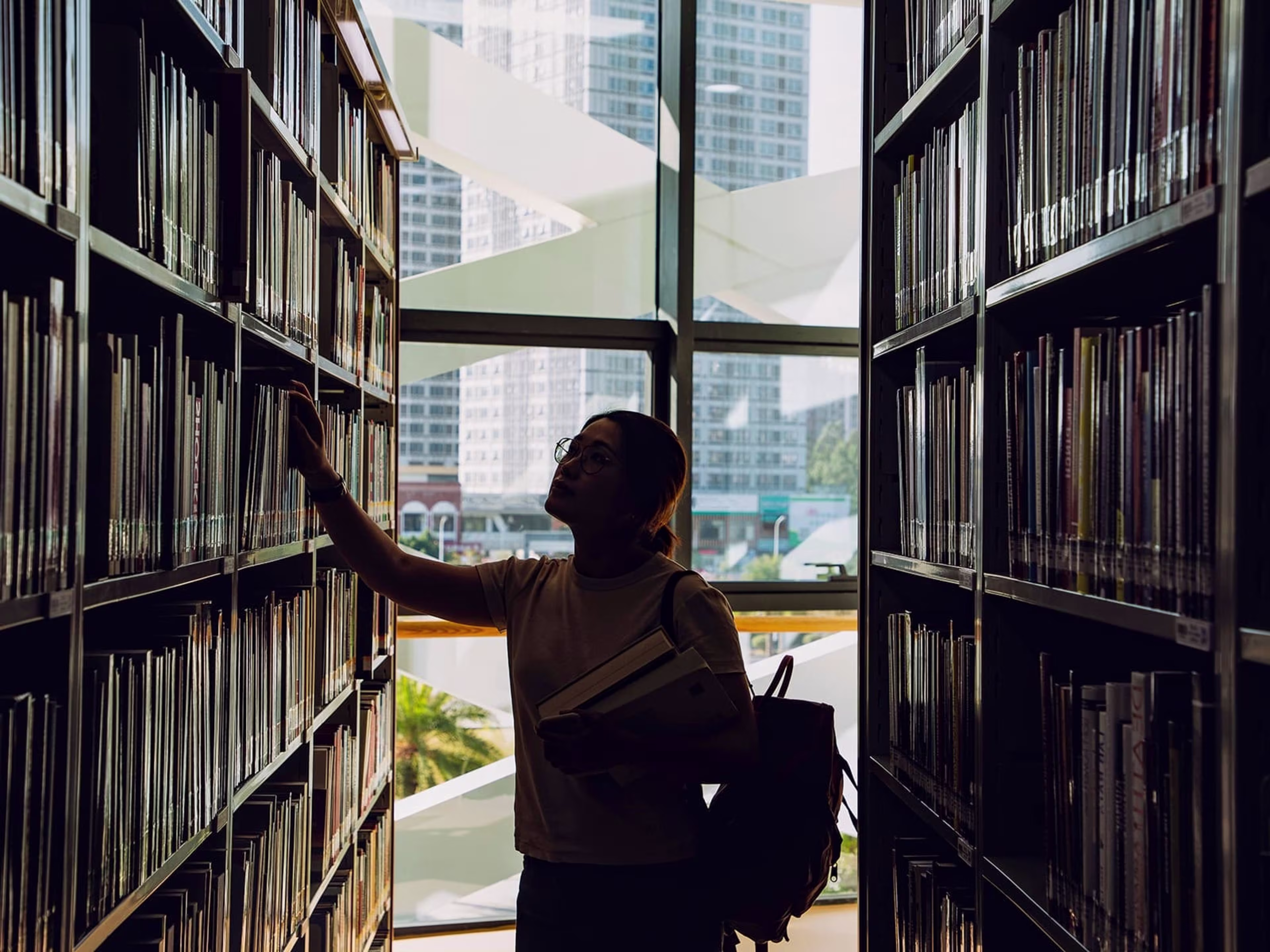 Girl in library pulling a book off the shelf
