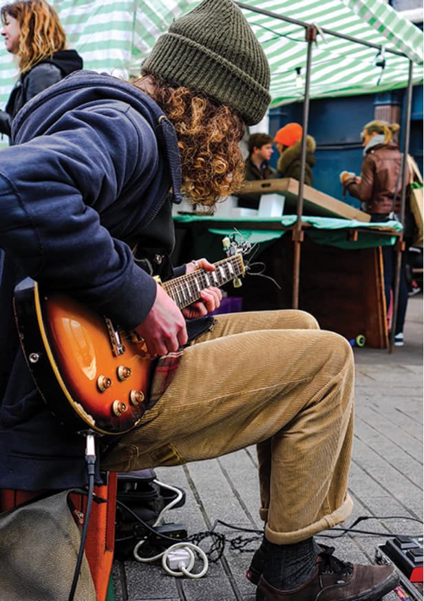 Man playing a guitar at an event in downtown Kitchener