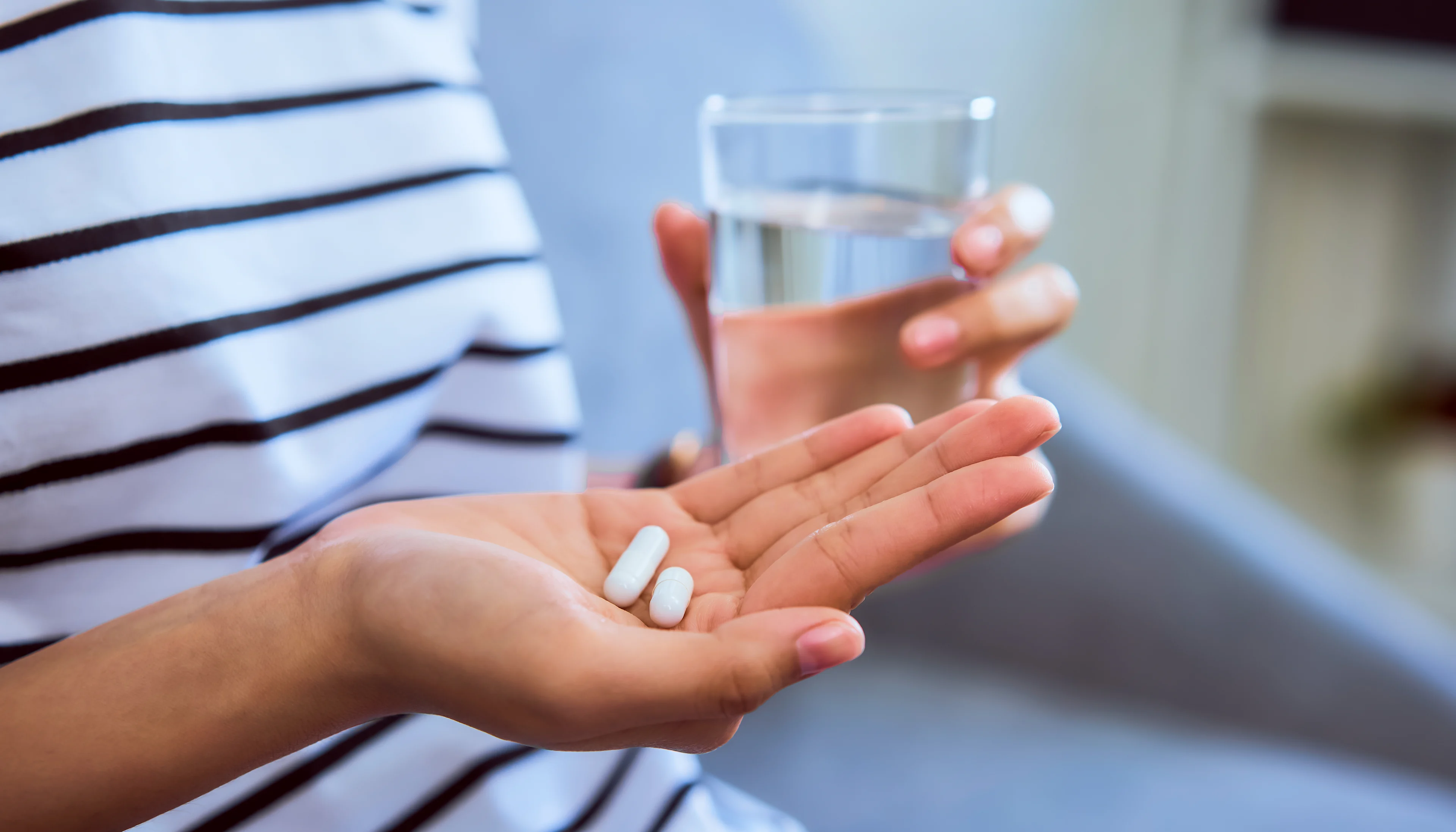 Slaapmiddelen zonder recept: veilig en effectief? - Hand met tabletten en een glas water