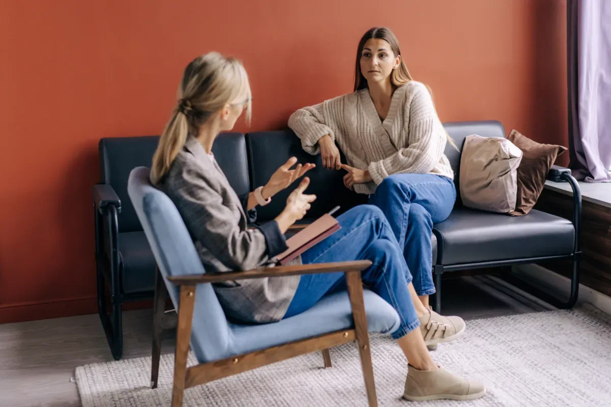 Zorgprofessional - vrouw in gesprek met zorgprofessional in huiselijke setting