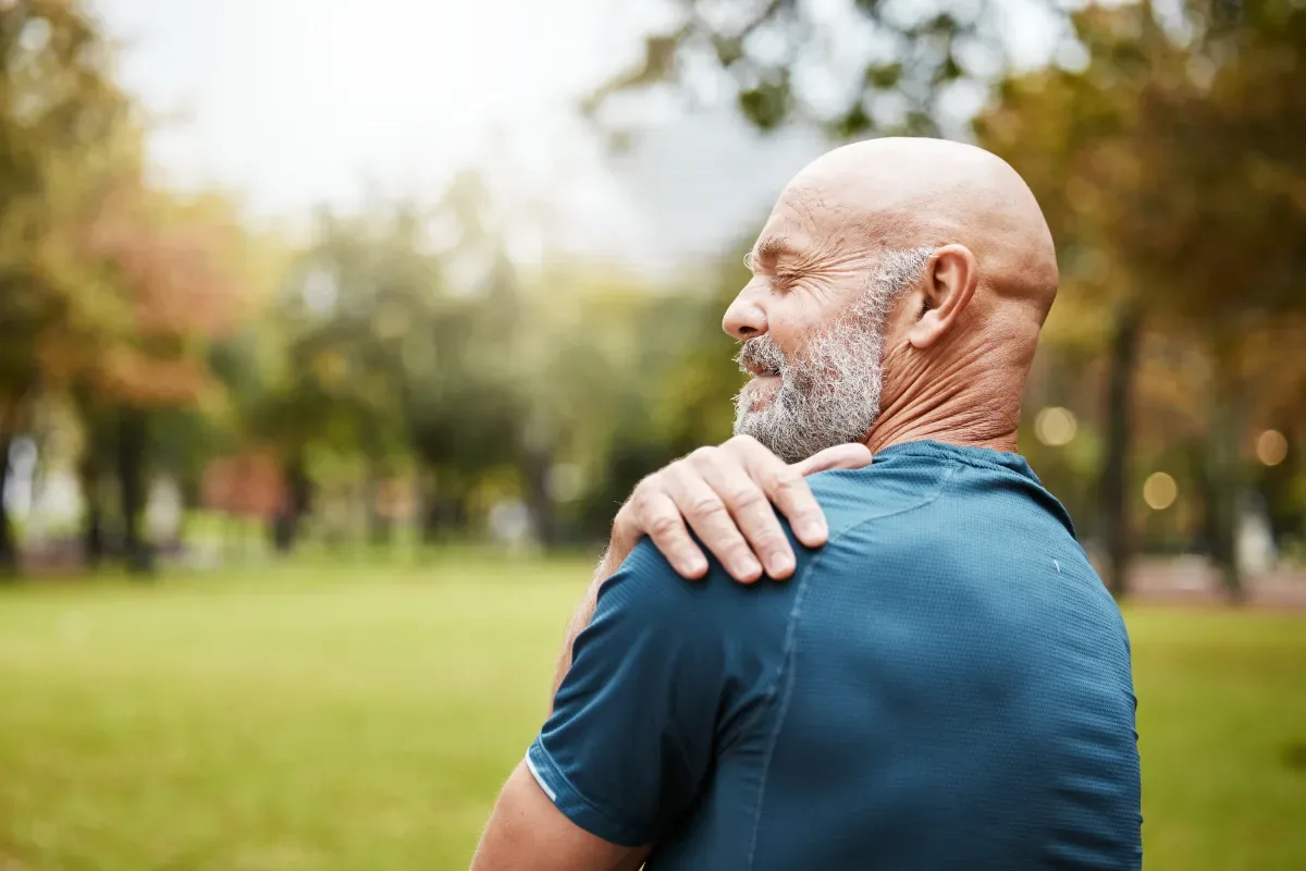 Stress klachten en symptomen bij mannen en vrouwen - man grijpt naar schouder in park
