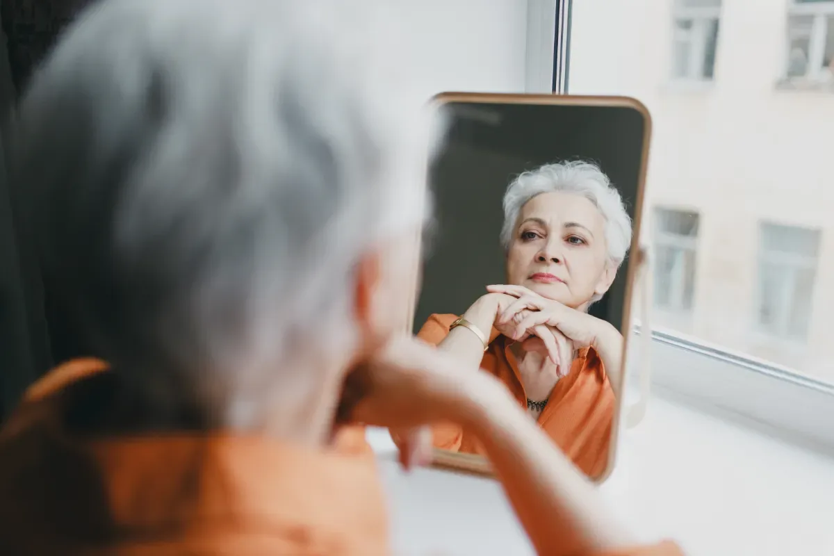 Zelfvertrouwen vergroten: praktische tips - vrouw kijkt zichzelf onzeker aan in spiegel
