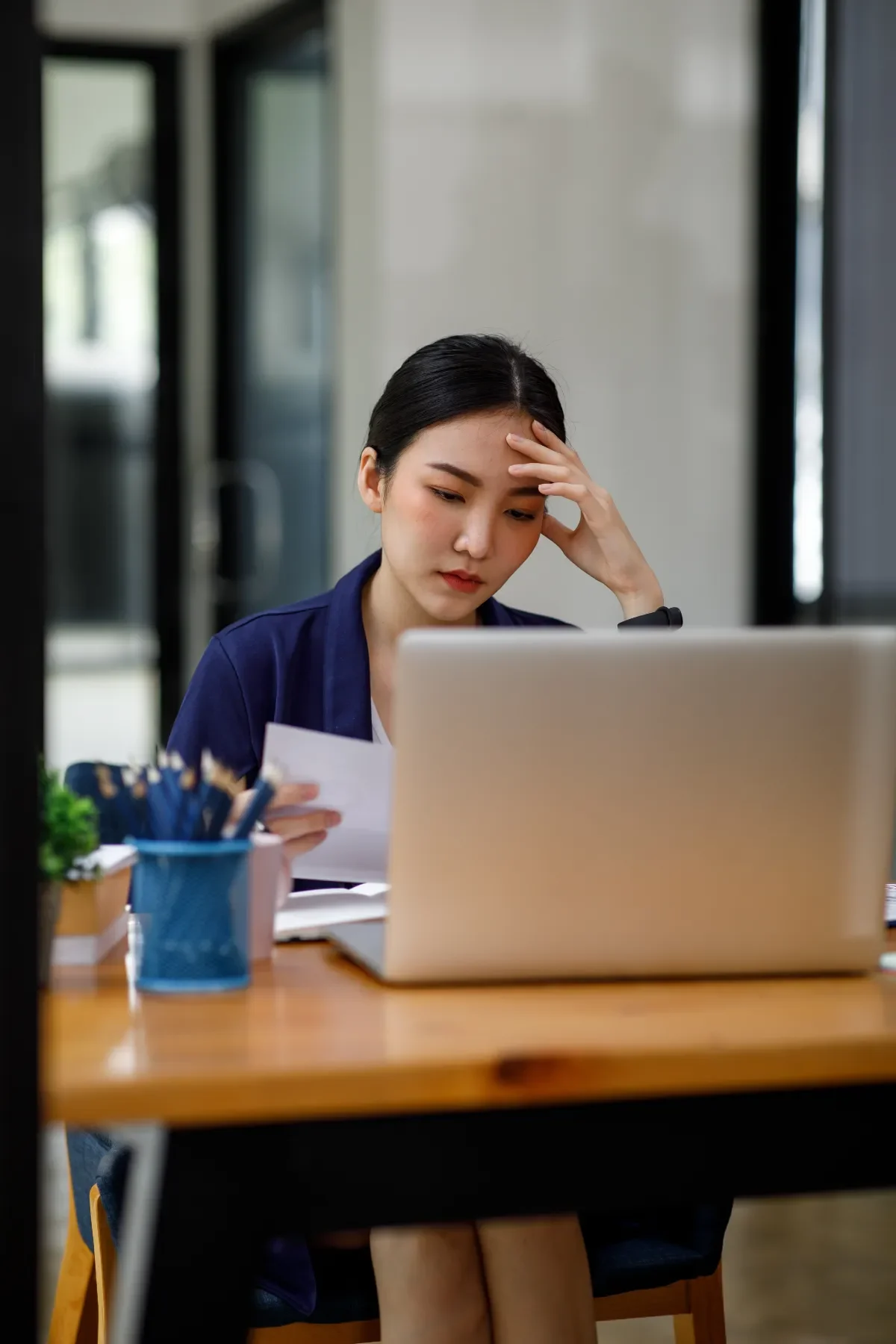 Werkdruk - vrouw achter laptop grijpt naar hoofd
