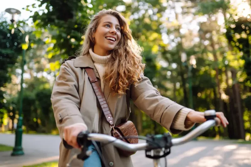 Gezonde leefstijlcoaching: samen aan de slag - vrolijke jonge vrouw op fiets in park