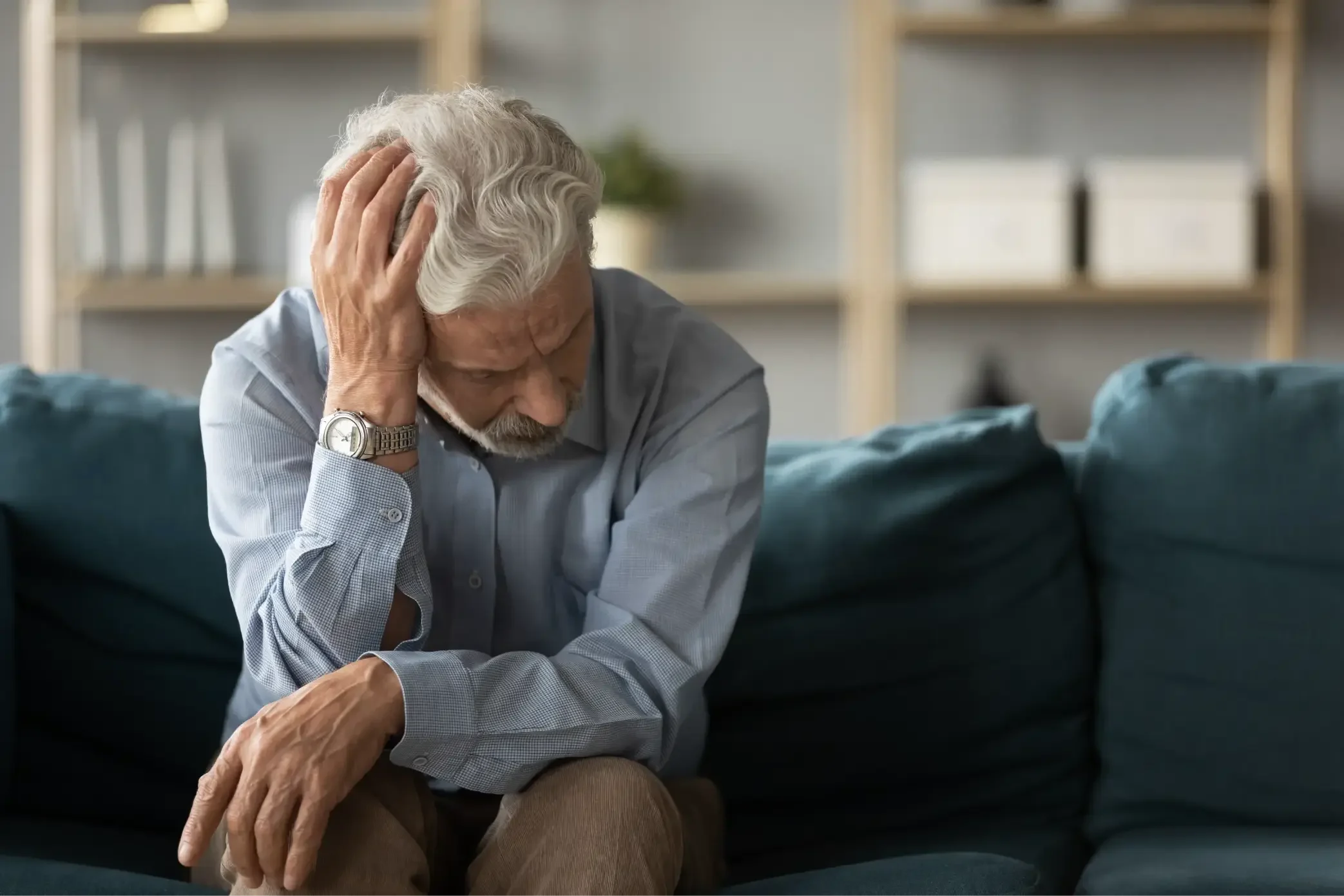 Wat is een posttraumatische stressstoornis (PTSS)? - man op bankstel grijpt naar hoofd