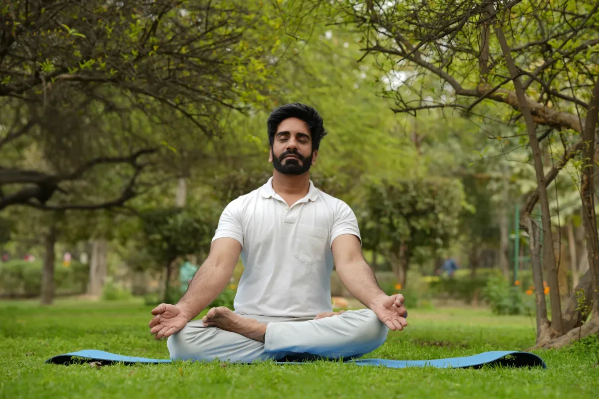 Ontspanningsoefeningen bij stress: waarom zijn ze zo belangrijk? - man zit in yoga positie in natuur