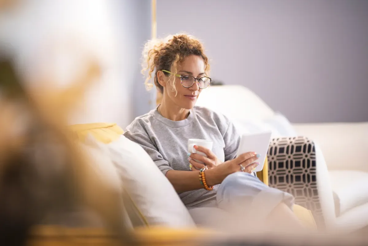 Praktische tips om te starten - vrouw leest e-reader op bankstel met kop koffie