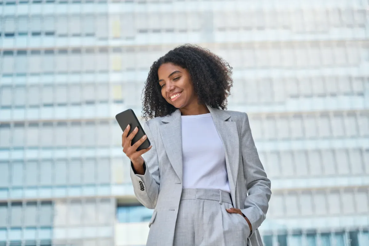 Positieve emotie - zakenvrouw kijkt naar telefoon voor groot gebouw