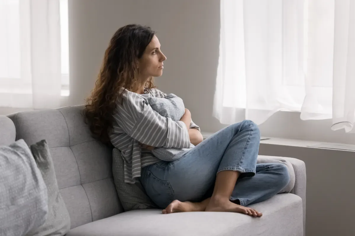 Verdrietig zijn hoort bij het leven – maar het mag niet overheersen - vrouw met armen over elkaar op bankstel
