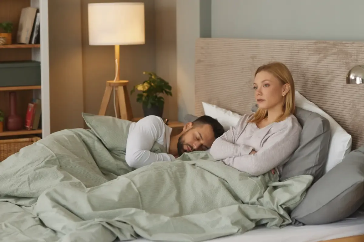 Insomnia behandeling: wat helpt echt? - man slaapt en vrouw ligt wakker in bed