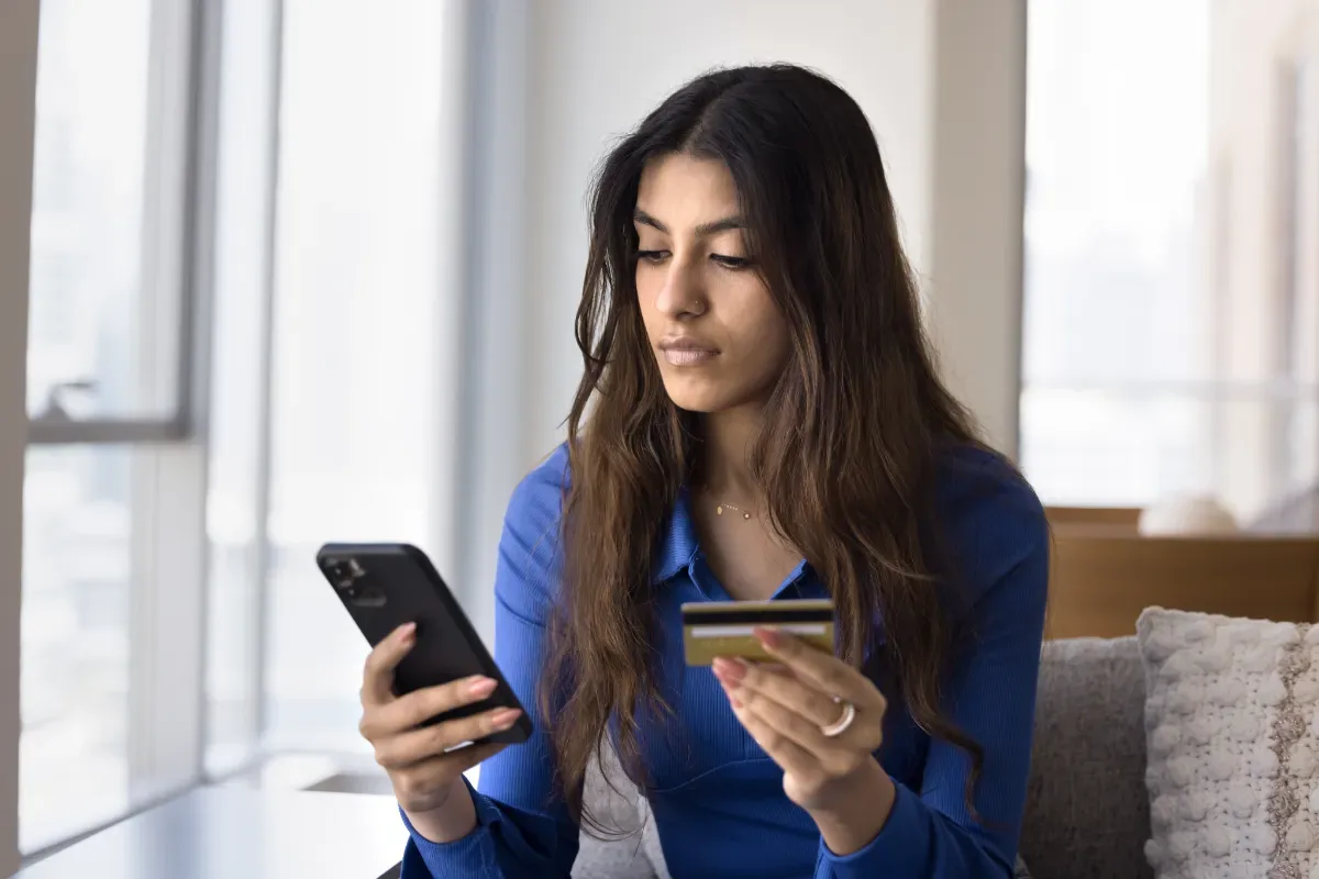 Financiële hulp gemeente: jouw eerste stap naar ondersteuning - vrouw met telefoon en pinpas in hand