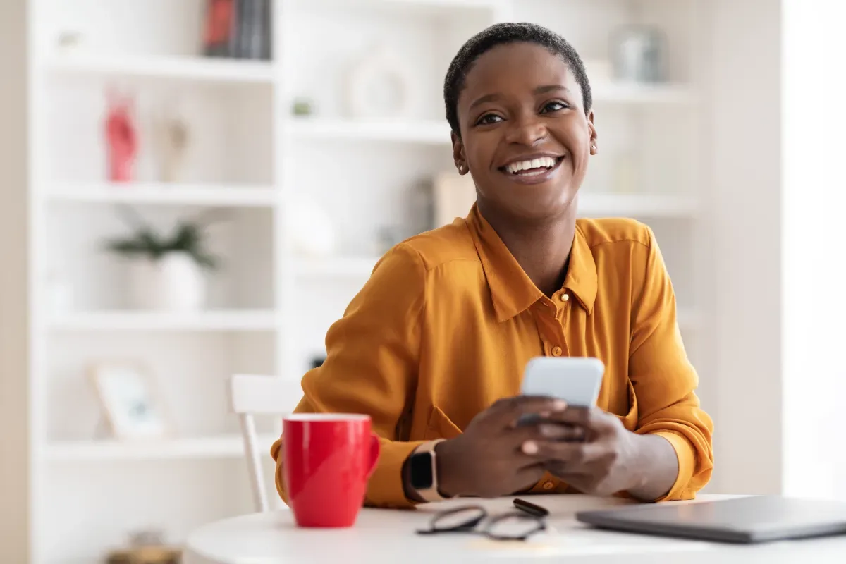 Positieve emotie - blije vrouw met koffie en telefoon in hand