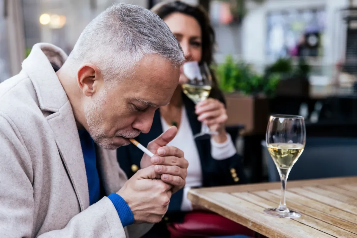 Stoppen met roken: met of zonder hulpmiddelen - man steekt sigaret op op terras