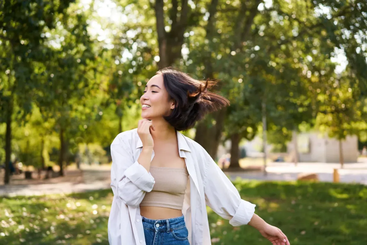 Positieve emotie - jonge vrouw zwaait met armen in natuur