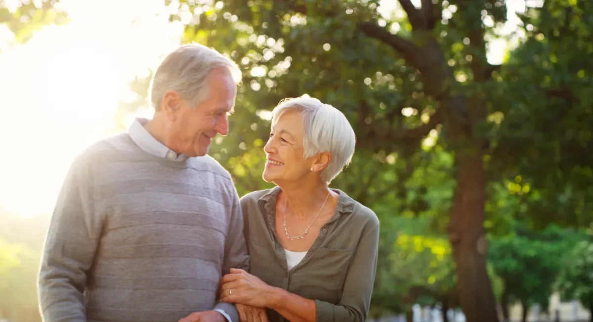 Positieve emotie - oude man en vrouw kijken blij naar elkaar in natuur