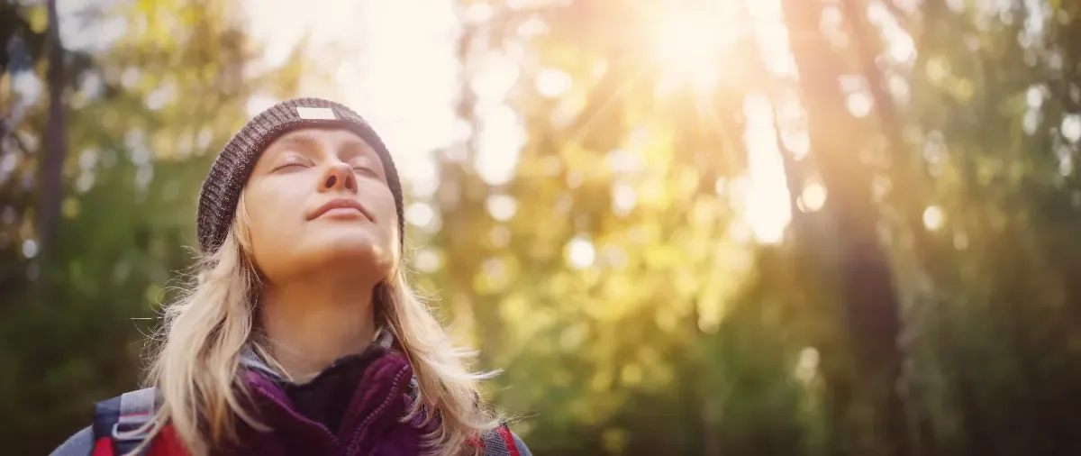 Mindful leven - vrouw in natuur geniet van zon met ogen dicht