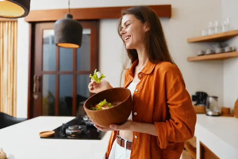 Gezond avondeten: voedzaam, lekker en goed voor je welzijn - vrouw geniet van salade in keuken