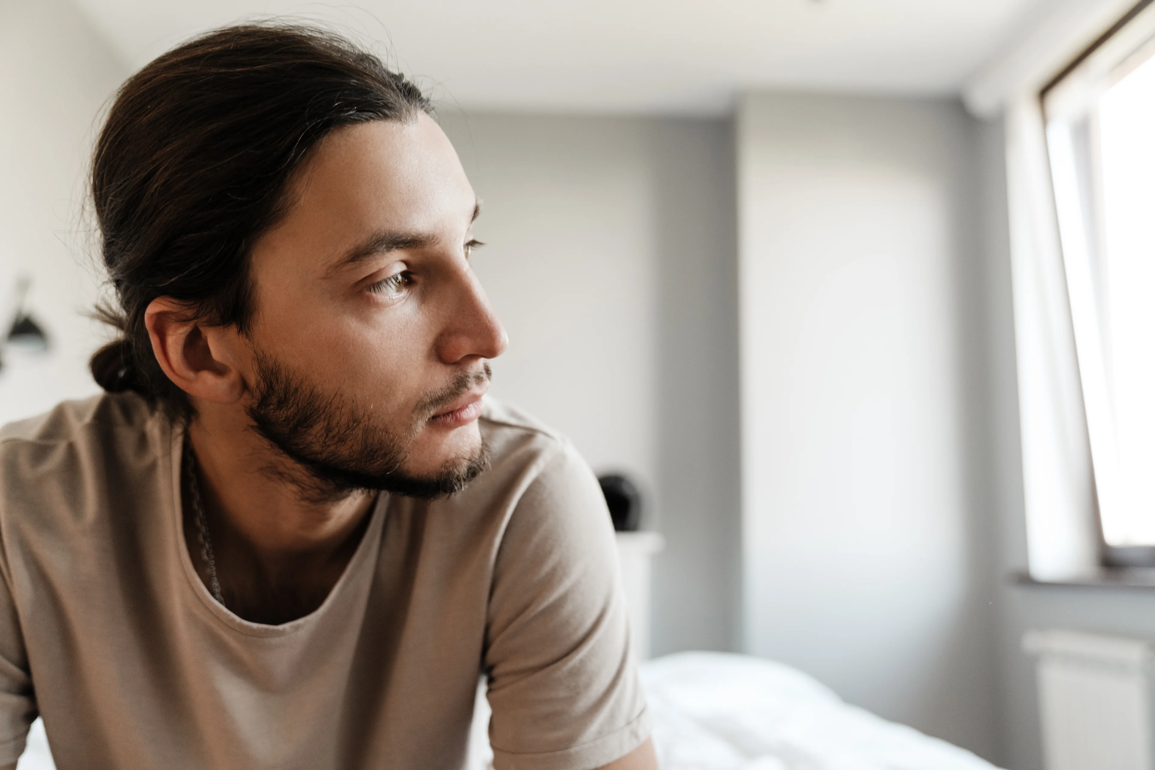 Klachten bij depressie ontstaan vaak geleidelijk - Jonge man zit op zijn bed