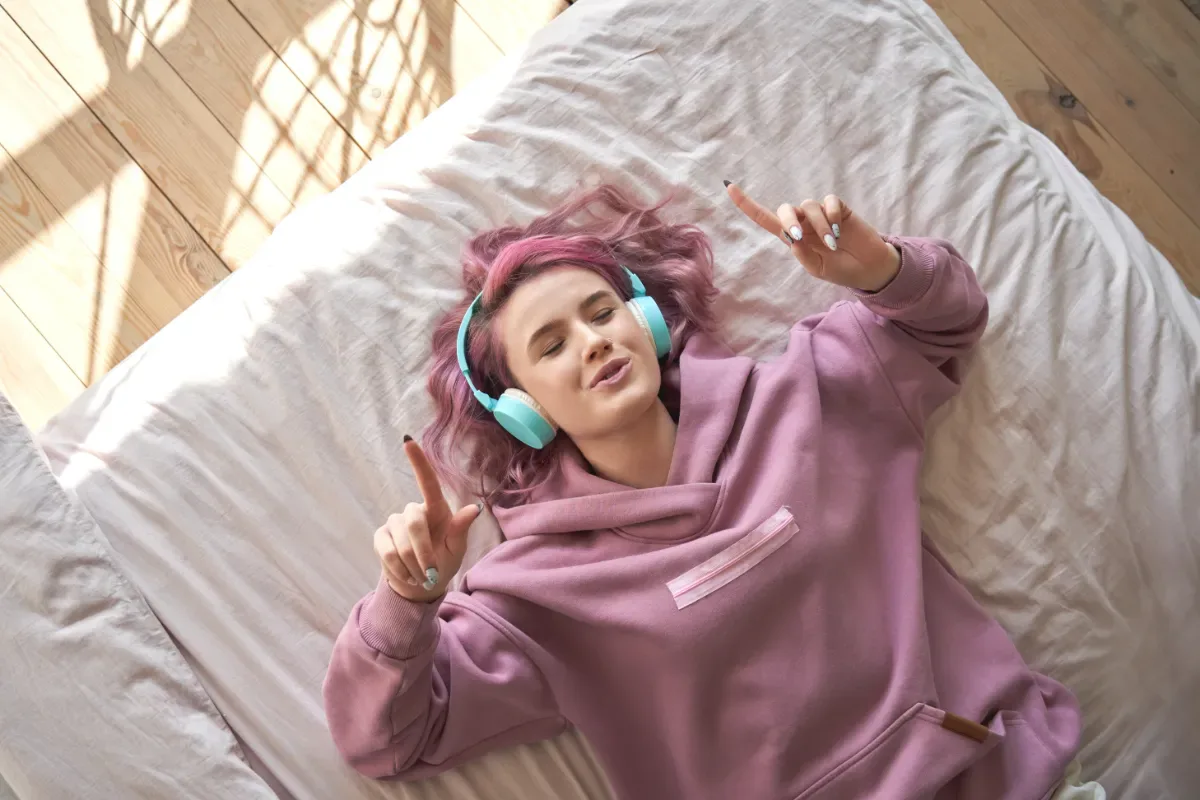 Ontspannen - jonge meid ligt ontspannen op bed naar muziek te luisteren