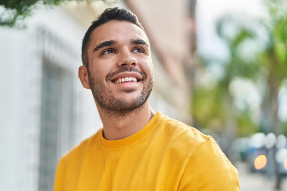 Positieve emotie - jonge man in stad kijkt vrolijk omhoog