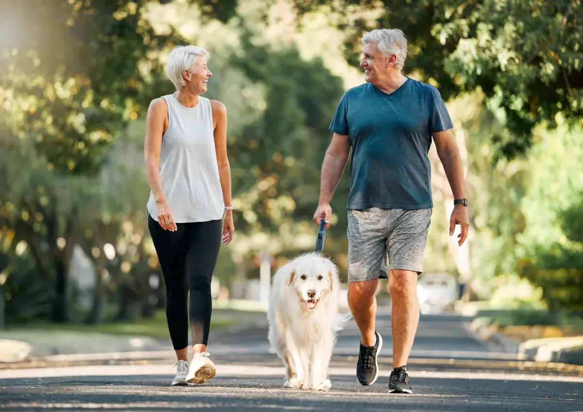 Positieve emotie - oude man en vrouw kijken naar elkaar tijdens wandeling in natuur met hond