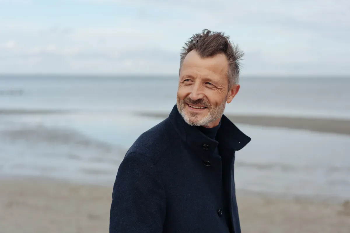 Wat kun je zelf doen bij stress klachten? - man kijkt achterom tijdens strandwandeling