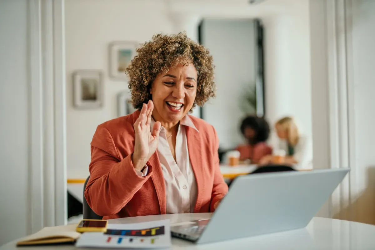 Positieve emotie - vrouw met krullen zwaait vrolijk naar laptop