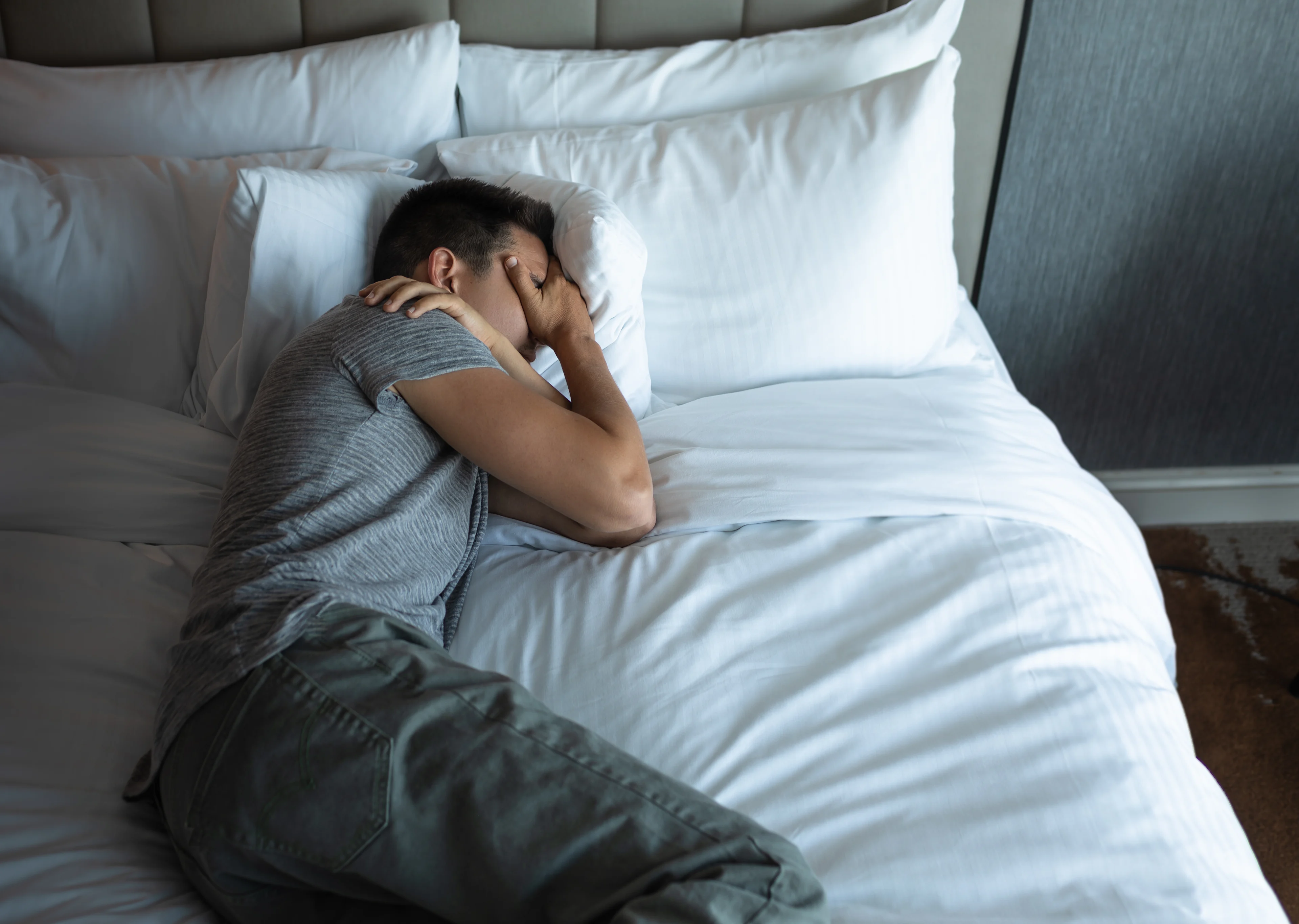 Wat is PTSS - Man ligt in bed met hand voor zijn ogen 