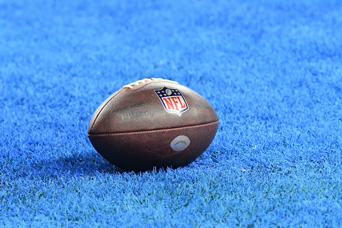 An NFL football sitting on a blue field.