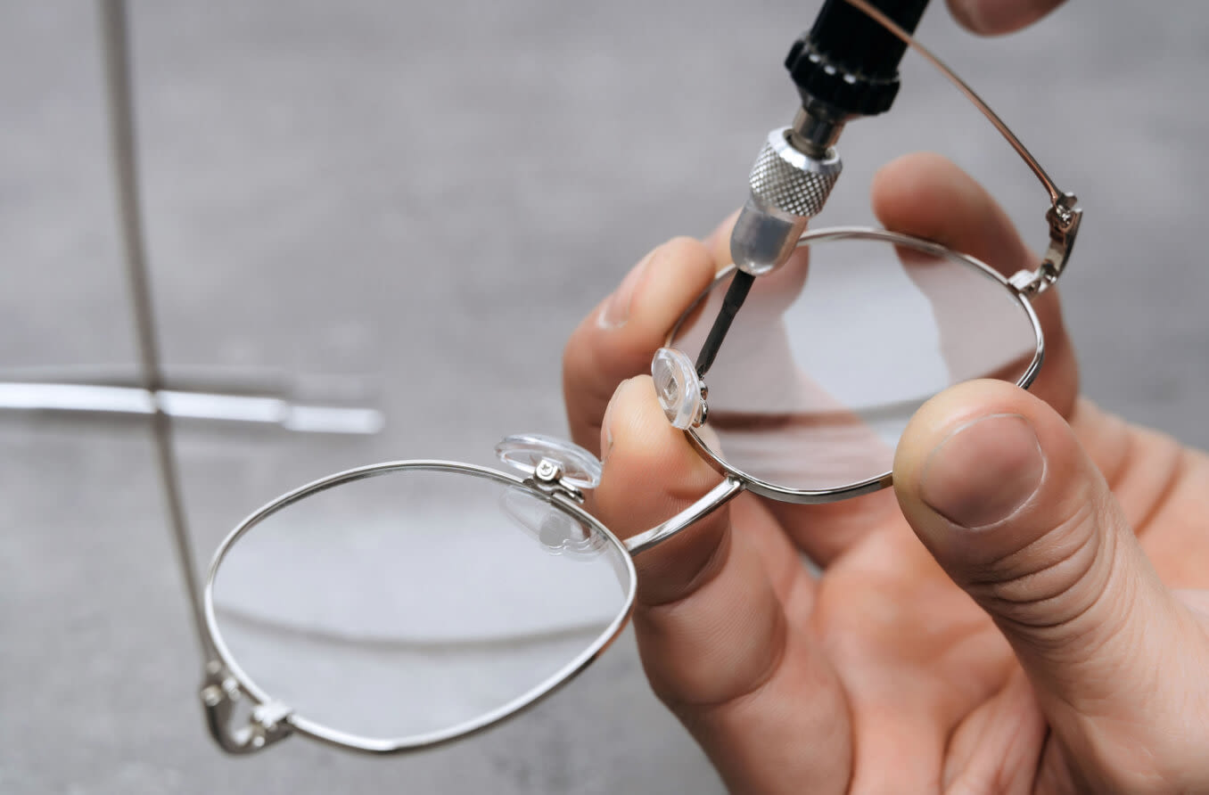 Person repairing broken eyeglass nose pads.